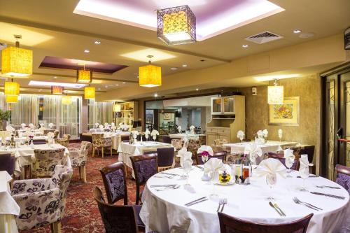 a dining room with tables and chairs with white tablecloths at Balneo Complex & Spa Aquatonik in Velingrad