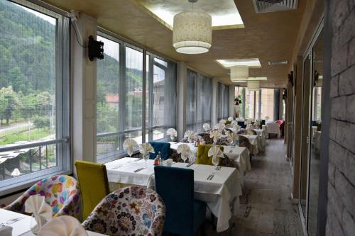 a restaurant with white tables and chairs and windows at Balneo Complex & Spa Aquatonik in Velingrad