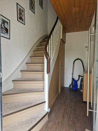 una escalera en una casa con paredes blancas y suelo de madera en Ferienwohnung A&K, en Bottrop