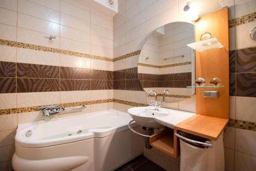 a bathroom with a sink and a tub and a mirror at Urania Luxury Suite with pool view -Loutra Resort in Loutra