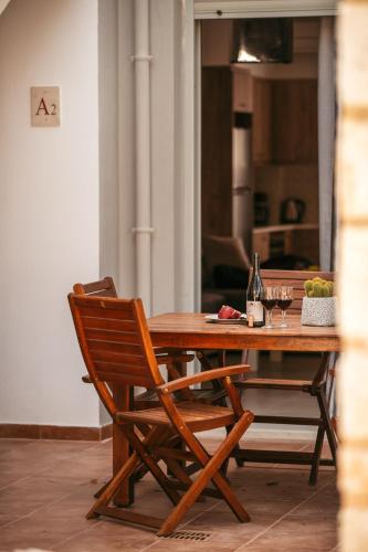 a wooden table with two chairs and wine glasses at Urania Luxury Suite with pool view -Loutra Resort in Loutra