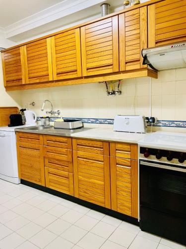 a kitchen with wooden cabinets and a sink and a stove at Sesimbra Flat in Sesimbra
