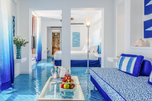 Ein blau-weißes Zimmer mit einem Bett und einem Tablett mit Obst. in der Unterkunft Capo la Gala Hotel&Wellness in Vico Equense