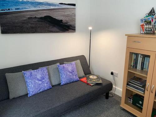 a living room with a gray couch with pillows at Cosy Seaside Hideaway in Northumberland with 1 pet welcome from November to March in Newbiggin-by-the-Sea