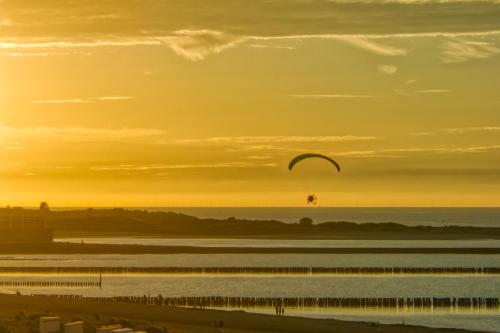 a paraglider flying over the water at sunset at Dormio Breskens Apartments & Penthouses in Breskens