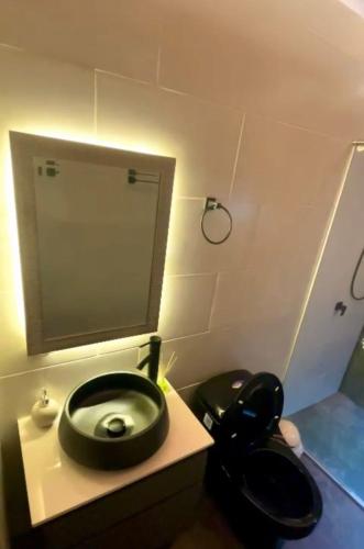 een badkamer met een toilet en een zwarte stoel bij Glamping Oro Verde in Santa Fe de Antioquia