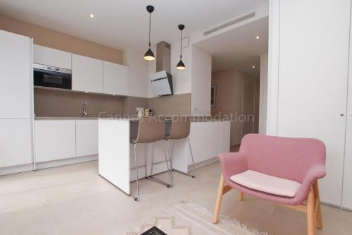 une cuisine avec des placards blancs et une chaise rose dans l'établissement Montrachet, à Cannes