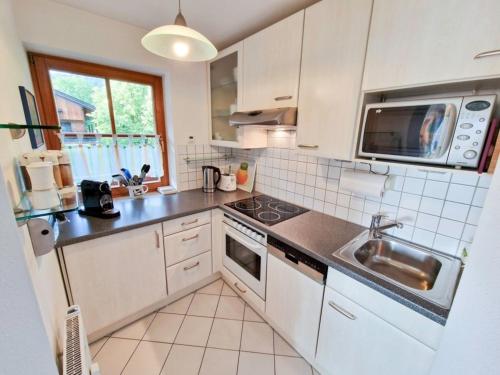 a white kitchen with a sink and a microwave at Sonnenwinkl in Reit im Winkl