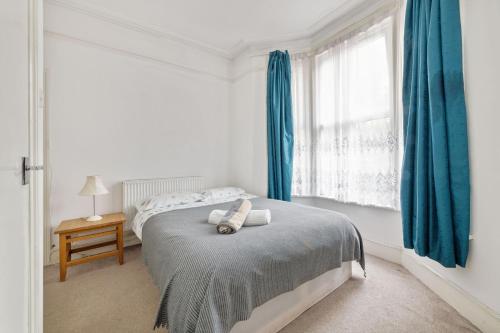 a bedroom with a bed with blue curtains and a window at Calderon Road in London