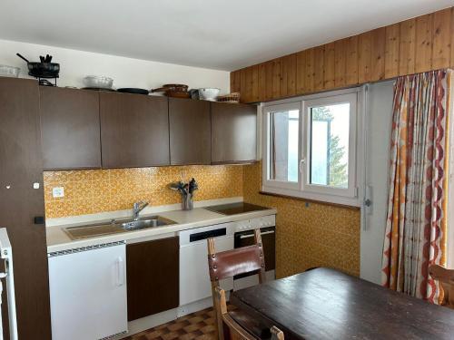 kuchnia ze zlewem, stołem i oknem w obiekcie Diablerets SKI LIFT & MOUNTAIN apartments w mieście Veysonnaz