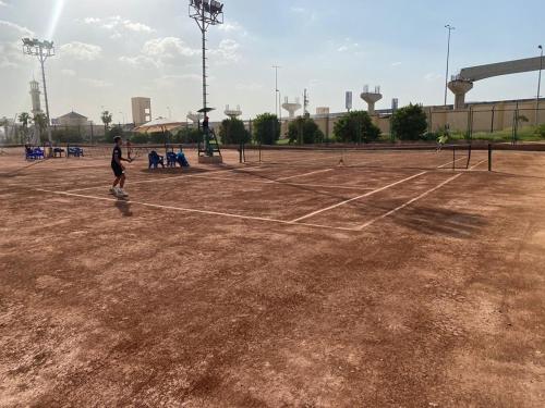 a man is playing tennis on a tennis court at Grand Plaza Hotel & Resort in Qaryat ash Shamālī