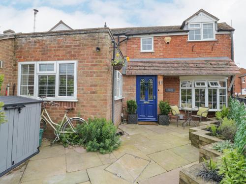 a brick house with a blue door and a patio at Jubilee Cottage in Stratford-upon-Avon