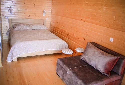 ein Schlafzimmer mit einem Bett und einem Sofa darin in der Unterkunft Arkhilo's cottage in Dedoplis Tskaro