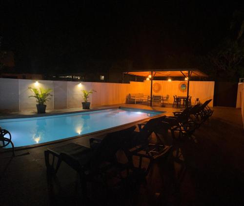 a swimming pool at night with chairs and tables at MANDEVILLA in Saint-Joseph