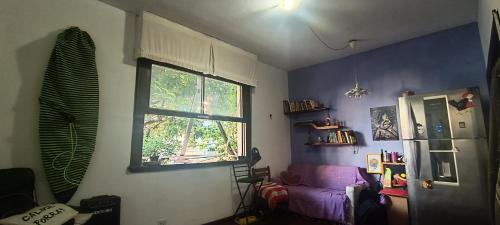 a living room with a window and a purple couch at Mini quarto in Rio de Janeiro