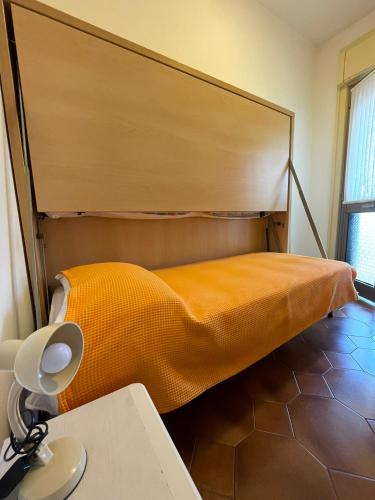 a bedroom with a large bed with an orange blanket at Appartamenti Residence Foscolo in Lido di Jesolo