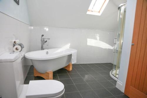 a white bathroom with a toilet and a bath tub at The Maypole at Wellow in Ollerton