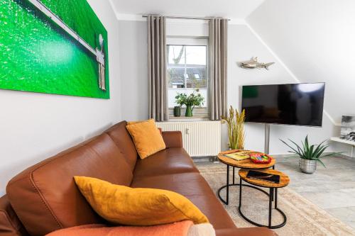 a living room with a brown couch and a tv at Birkenstraße 6 Haus II Whg6 in Zingst