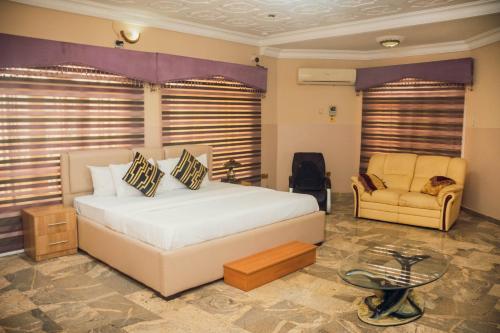 J's Place Hotel في أبوجا: غرفة نوم بسرير واريكة وكرسي