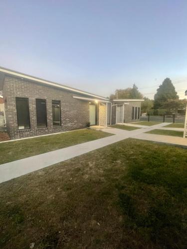 a brick building with a grass yard in front of it at Four Square Short Stay Accommodation Railton in Railton
