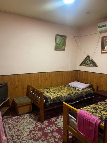 Pokój z dwoma łóżkami i telewizorem w obiekcie Sohil boyi w mieście Fergana