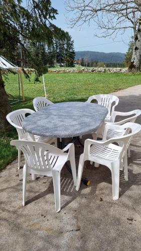 a picnic table with four white chairs around it at Studio à la ferme in La Brévine