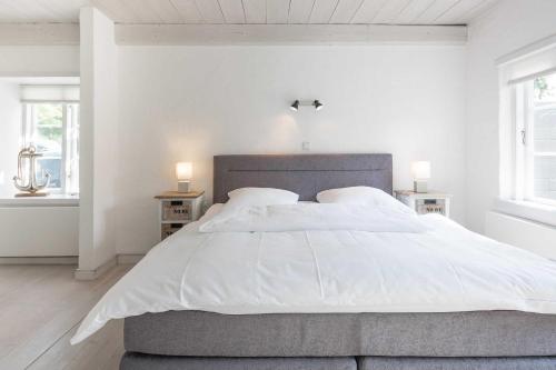 a white bedroom with a large bed with white sheets at FeWo Watt-Lounge zwischen Husum und Nordstrand in Wobbenbüll