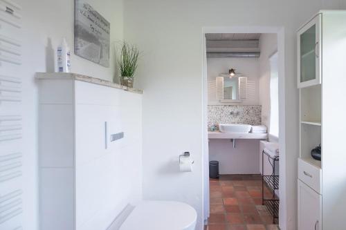 a white bathroom with a toilet and a sink at FeWo Watt-Lounge zwischen Husum und Nordstrand in Wobbenbüll