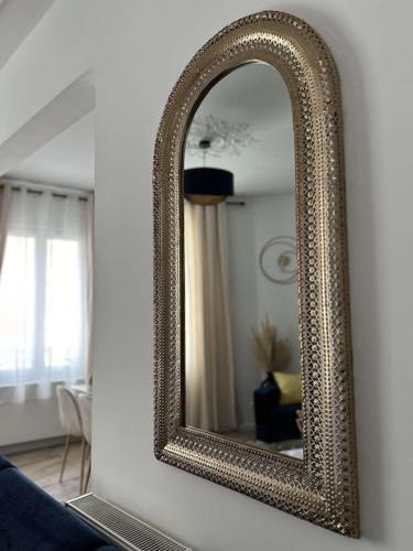 un miroir à cadre doré sur un mur dans un salon dans l'établissement Beau Séjour, à Épernay
