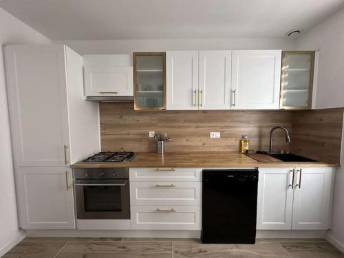 une cuisine avec des armoires blanches, un évier et une cuisinière dans l'établissement Beau Séjour, à Épernay