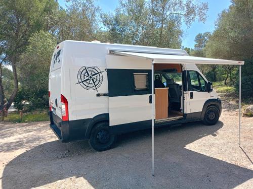a white van with a canopy in a parking lot at Furgoneta Camper Gran Volumen in Palma de Mallorca