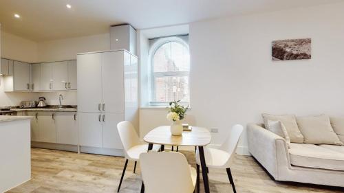 Abertillery的住宿－Spacious three bedroom apartment with Valley views，厨房以及带桌子和沙发的客厅。