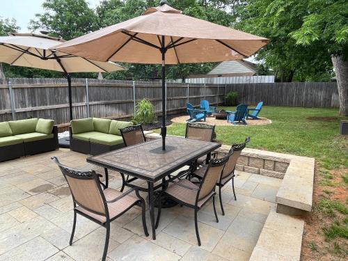 a table and chairs with an umbrella on a patio at Stylish townhome near AT&T Stadium, Globe Life, Six Flags & More in Arlington