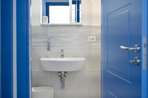 ein Badezimmer mit einem Waschbecken und einer blauen Tür in der Unterkunft Appartamento Dreaming Avola in Avola