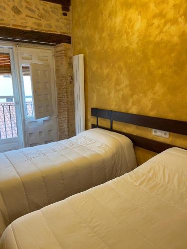 two beds in a bedroom with a yellow wall at La Casona de 1717 in El Burgo de Osma
