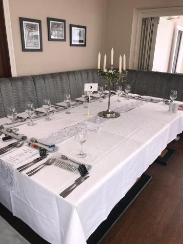 a long white table with glasses and candles on it at The Maypole at Wellow in Ollerton