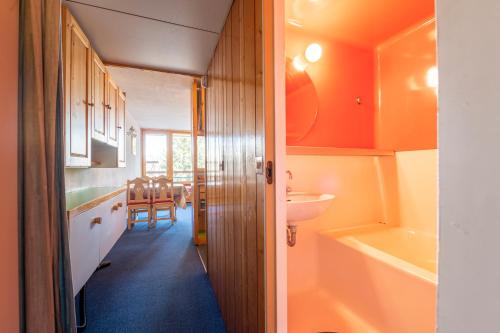 La salle de bains est pourvue de murs orange, d'un lavabo et de toilettes. dans l'établissement Beau Studio Lauzieres 11 Arc, à Bourg-Saint-Maurice