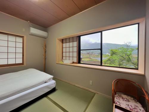 a bedroom with a bed and two windows with a view at 湯布院我楽珍民泊Yufuin Garakuchin in Yufu