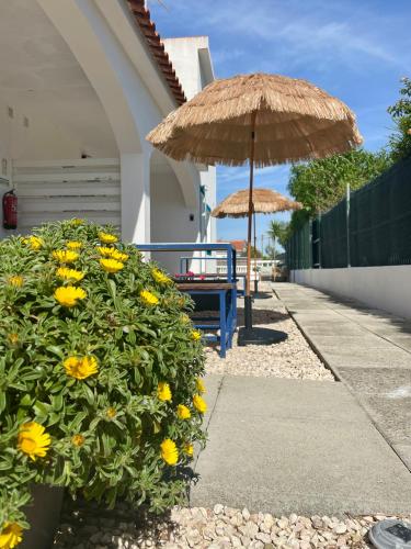 two umbrellas and a bench and a table with yellow flowers at California Dream Inn in Aljezur