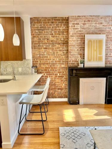 a kitchen with a brick wall and white chairs at 318-2 Bedroom 2 Bathroom Apt W In Unit Laundry in Hoboken