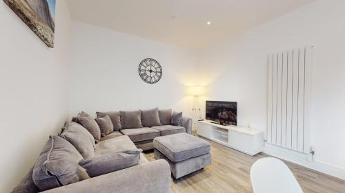 a living room with a couch and a clock on the wall at Spacious three bedroom apartment with Valley views in Abertillery