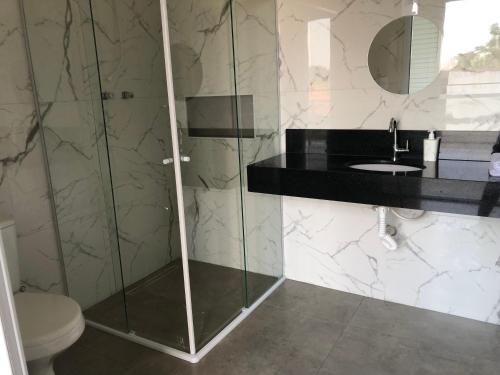 a bathroom with a shower with a toilet and a sink at Hospedaria Colinas in Indaiatuba