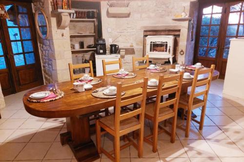 Chambre Aramis في Ayguetinte: طاولة وكراسي خشبية في غرفة بها موقد