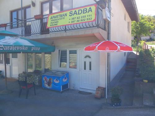un restaurante con sombrilla frente a un edificio en Apartman Sadba en Goražde