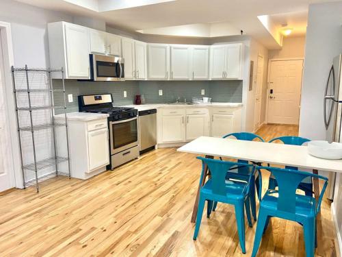 uma cozinha com armários brancos, uma mesa e cadeiras azuis em 205-Bright and Airy 2Bed 2 Bath Apartment in Hoboken em Hoboken