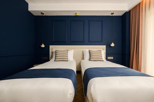two beds in a room with blue walls at XVI Suites - Adults Only in Naxxar