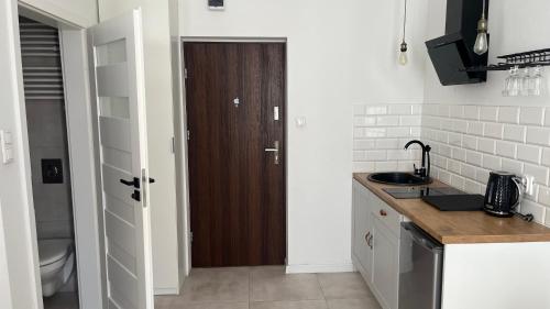 a kitchen with a sink and a wooden door at Kamienica Łódzka in Łódź