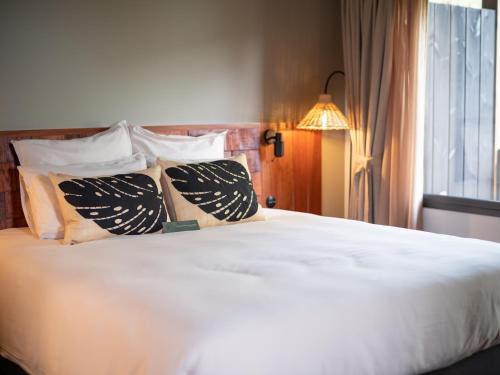 a bedroom with a white bed with pillows and a window at Hôtel le Tuit-Tuit in La Plaine des Palmistes