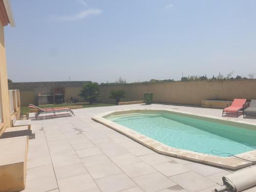 - une grande piscine sur une terrasse avec 2 chaises dans l'établissement Villa avec piscine en camargue, à Saint-Laurent-dʼAigouze