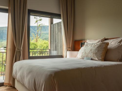 ein Schlafzimmer mit einem großen Bett und einem großen Fenster in der Unterkunft Hôtel le Tuit-Tuit in La Plaine des Palmistes